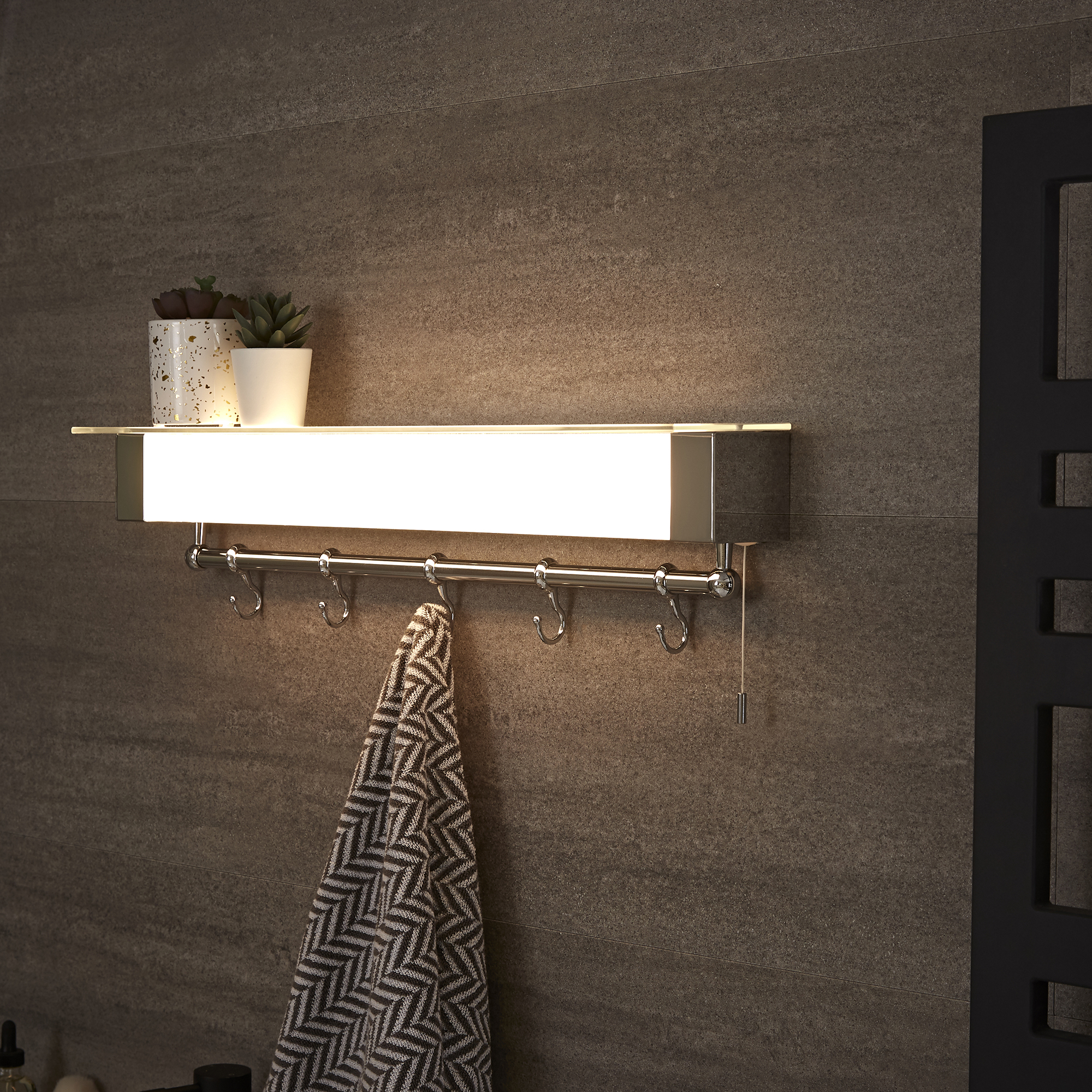 iluminacion ducha: toallero iluminado en la pared del baño con azulejos oscuros