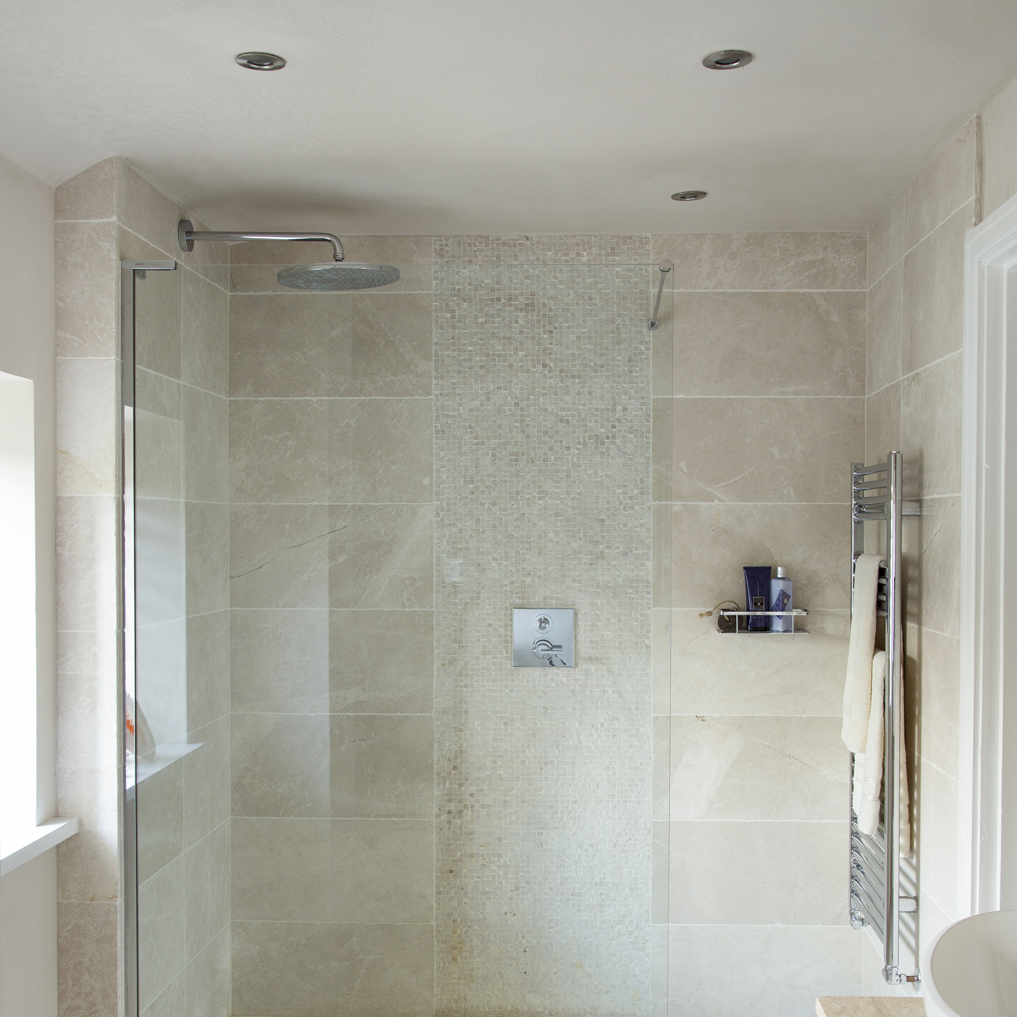 iluminacion zona ducha: ducha de azulejos neutros con panel de pared de mosaico. pantalla de cristal Casa propiedad de Livia Simoka y Pete Allibone. baño de piedra caliza